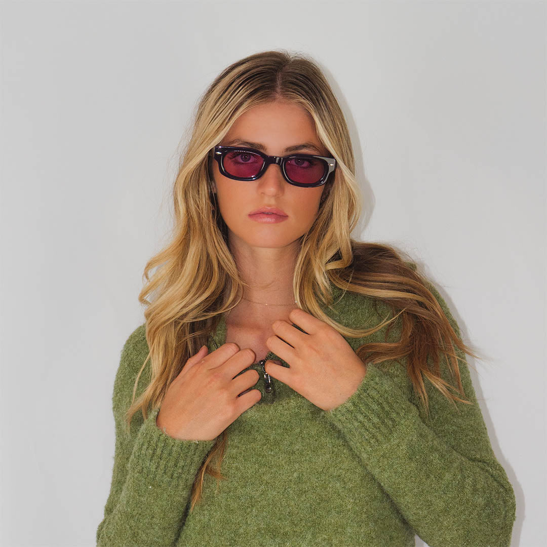 Female model wearing Kesera sunglasses featuring Aubergine acetate and purple lenses with UV protection