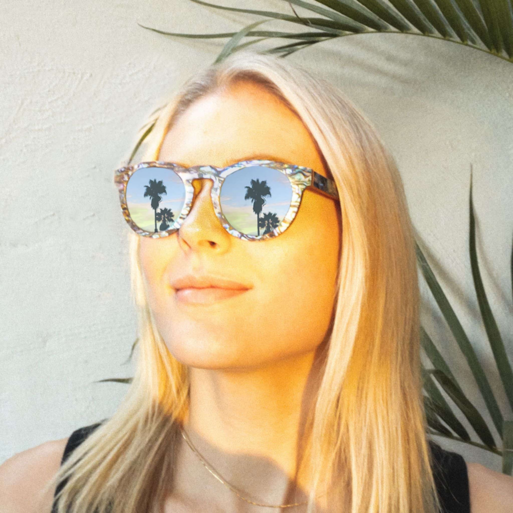 Alternate angle of model wearing Soul California Eyewear Pfeiffer Beach sunglasses featuring Zebra Wood & New Zealand Abalone Paua Shell frame and polarized blue lenses.